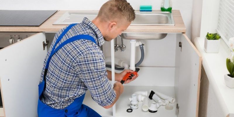 Plumber checking faucet under sink